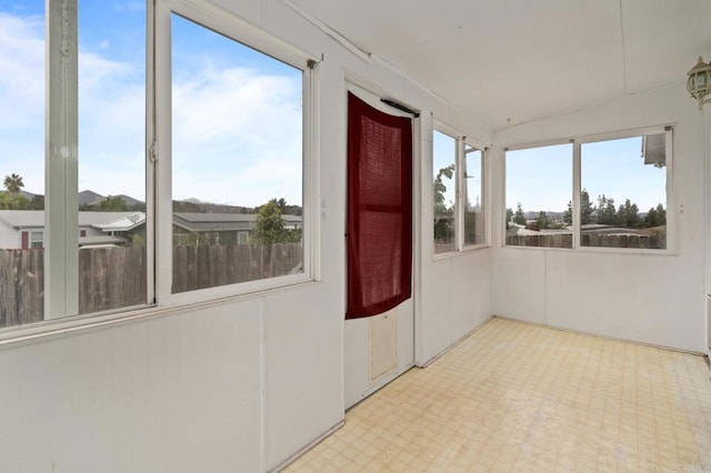 unfurnished sunroom featuring lofted ceiling and a healthy amount of sunlight