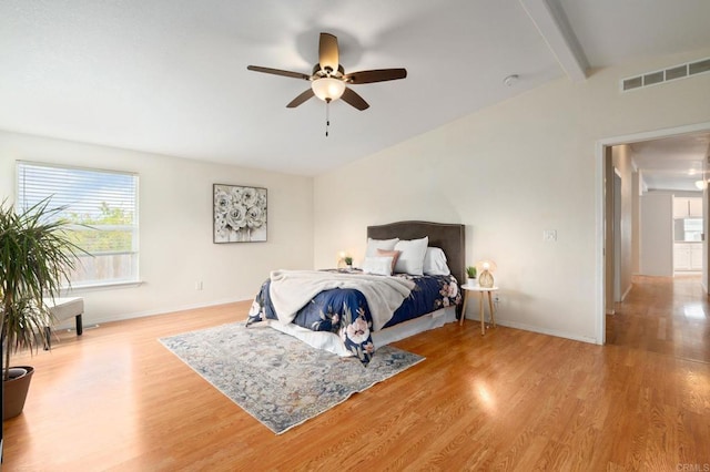 bedroom featuring multiple windows, beamed ceiling, ceiling fan, and light hardwood / wood-style flooring