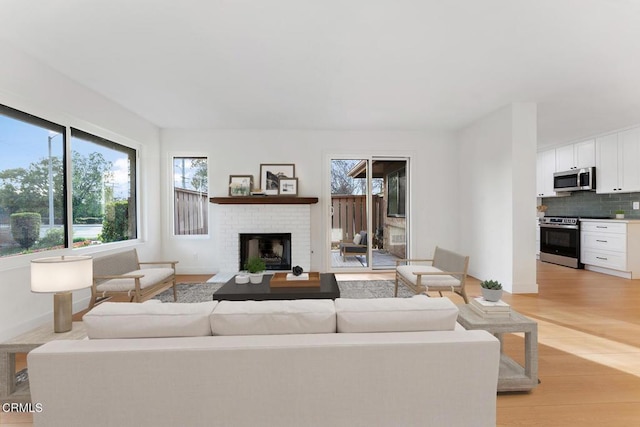 living room featuring a fireplace, light hardwood / wood-style flooring, and a wealth of natural light