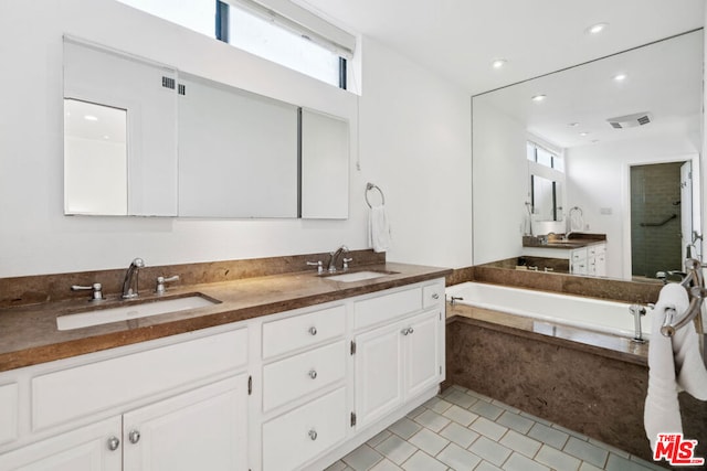 bathroom with vanity, tiled tub, and tile patterned flooring