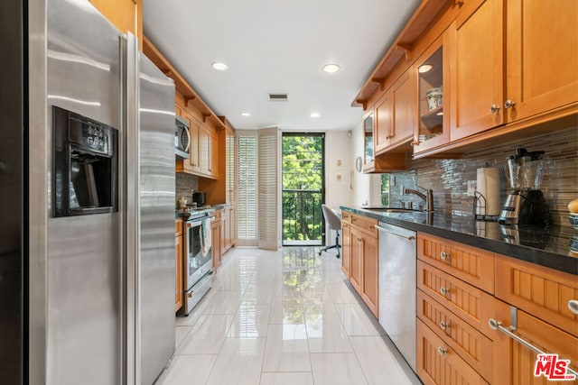 kitchen with sink, dark stone countertops, backsplash, expansive windows, and stainless steel appliances