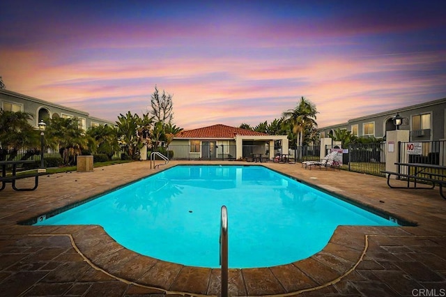 pool at dusk featuring a patio area