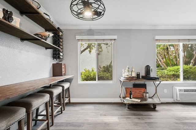 interior space with a wall unit AC, crown molding, baseboards, and wood finished floors