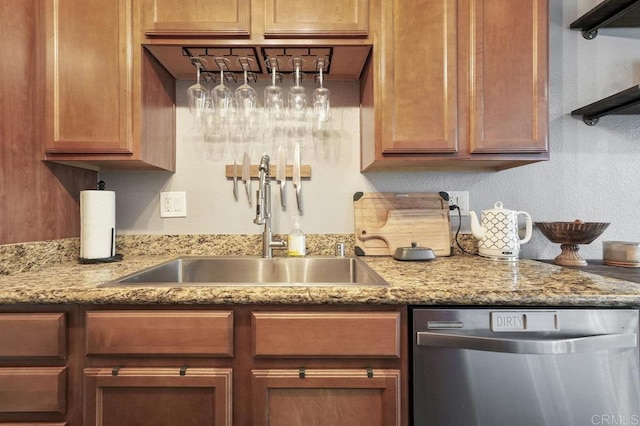 kitchen featuring dishwasher, a textured wall, a sink, and light stone countertops