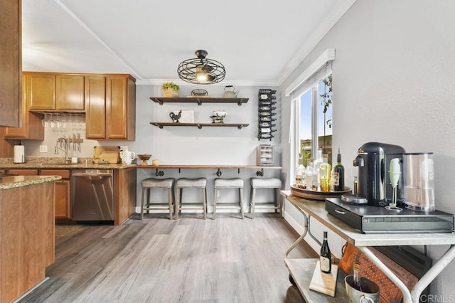 kitchen featuring ornamental molding, light stone counters, stainless steel dishwasher, and light wood finished floors