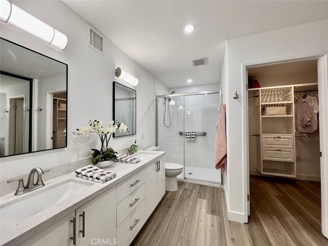 bathroom featuring a stall shower, visible vents, a sink, and wood finished floors