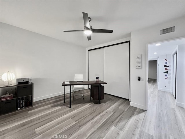 home office featuring light wood-style floors, visible vents, baseboards, and a ceiling fan