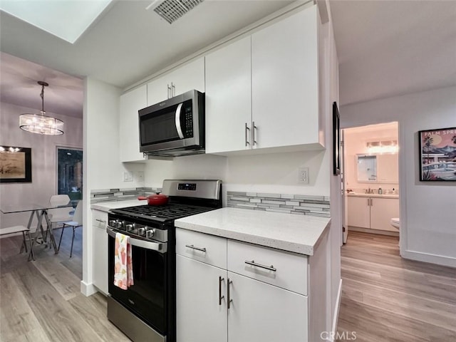 1137 Tiffany Cir S, Palm Springs, CA 92262 - kitchen with stainless steel appliances, light wood finished floors, white cabinets, and baseboards
