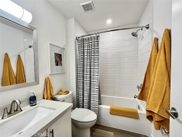 full bathroom featuring toilet, wood finished floors, vanity, visible vents, and shower / bath combination with curtain