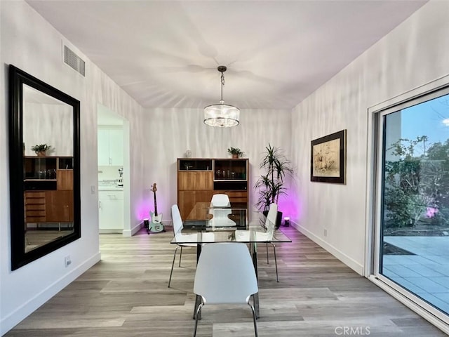 dining area featuring light wood-style floors, visible vents, a notable chandelier, and baseboards