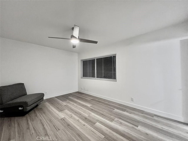 unfurnished room featuring a ceiling fan, light wood-type flooring, and baseboards