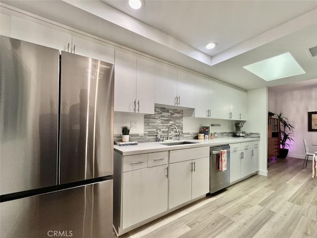 kitchen featuring light countertops, appliances with stainless steel finishes, a sink, and white cabinetry