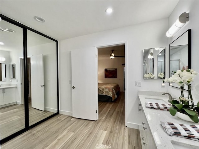 full bath featuring baseboards, connected bathroom, wood finished floors, vanity, and recessed lighting