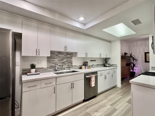 kitchen featuring stainless steel appliances, a sink, visible vents, white cabinetry, and light countertops