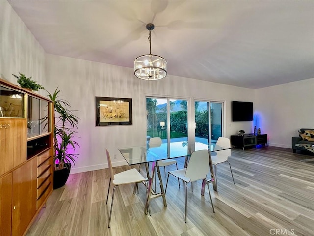 dining space with an inviting chandelier, light wood-style flooring, and baseboards