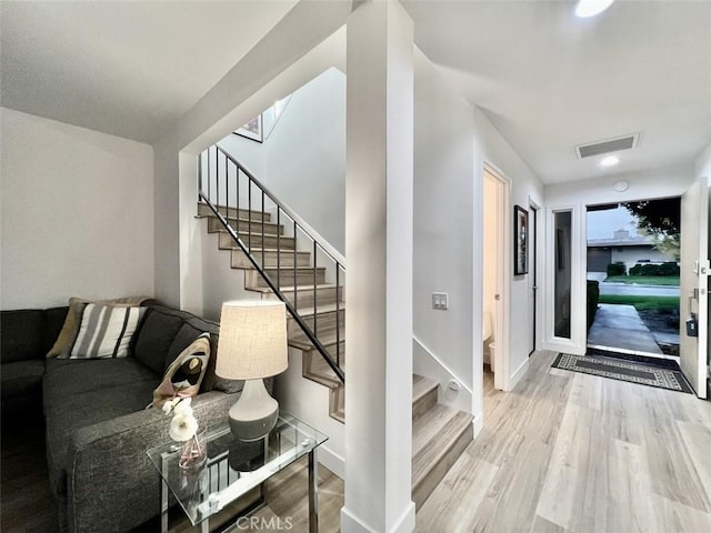 interior space featuring light wood-style floors, baseboards, stairs, and visible vents