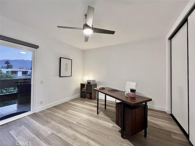 home office featuring light wood finished floors, a mountain view, and baseboards