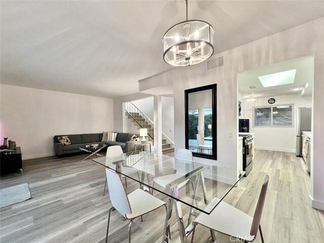 1137 Tiffany Cir S, Palm Springs, CA 92262 - dining room featuring light wood-style floors, stairway, a chandelier, a skylight, and baseboards