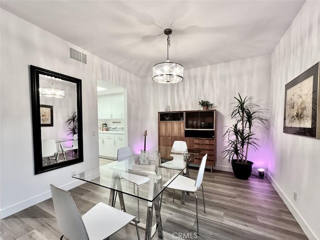 dining room with wood finished floors, visible vents, baseboards, and an inviting chandelier