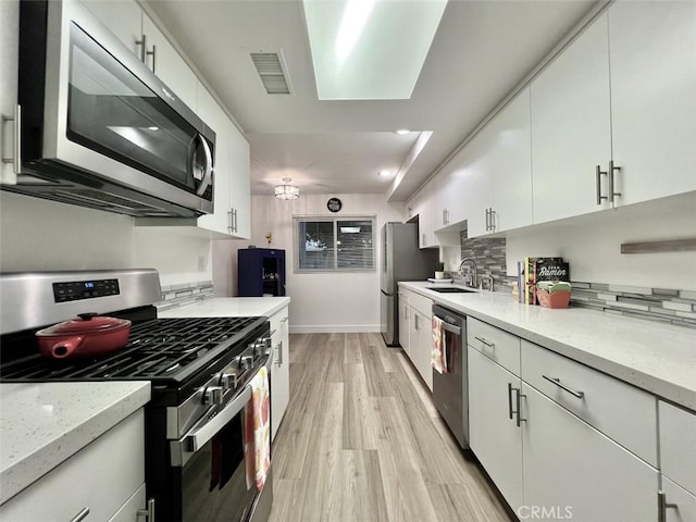 kitchen with stainless steel appliances, light countertops, and white cabinetry