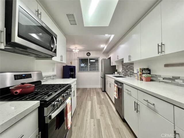 1137 Tiffany Cir S, Palm Springs, CA 92262 - kitchen featuring stainless steel appliances, white cabinets, decorative backsplash, light wood-style flooring, and light stone countertops
