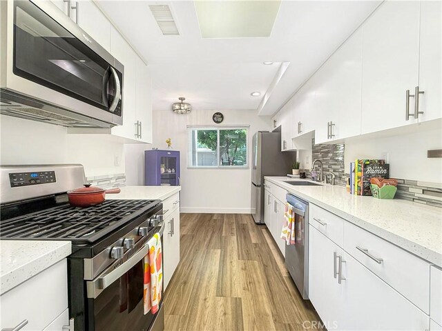 1137 Tiffany Cir S, Palm Springs, CA 92262 - kitchen with stainless steel appliances, light wood-style flooring, white cabinets, light stone countertops, and recessed lighting