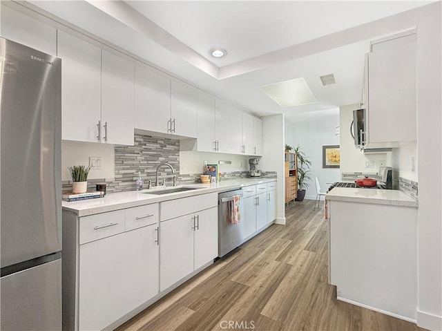 1137 Tiffany Cir S, Palm Springs, CA 92262 - kitchen with stainless steel appliances, light wood-style flooring, light countertops, white cabinetry, and recessed lighting