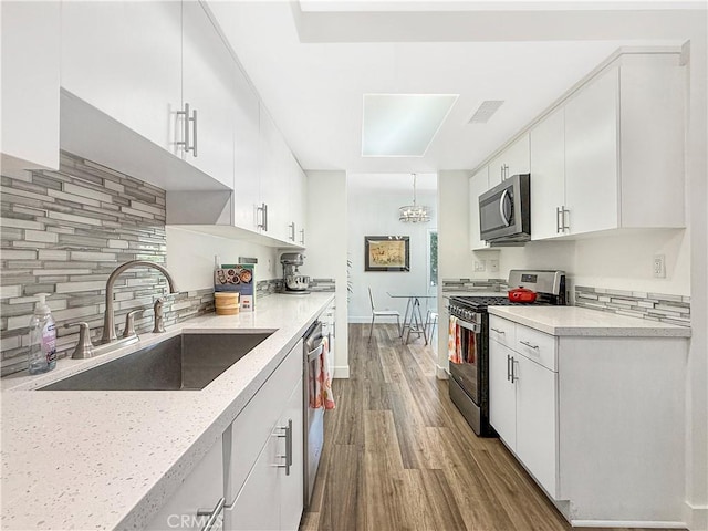1137 Tiffany Cir S, Palm Springs, CA 92262 - kitchen with stainless steel appliances, tasteful backsplash, wood finished floors, and white cabinetry