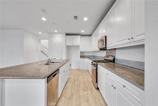 kitchen with sink, white cabinetry, an island with sink, stainless steel appliances, and light hardwood / wood-style floors