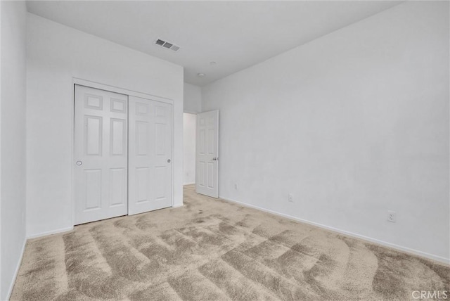 unfurnished bedroom with light carpet and a closet