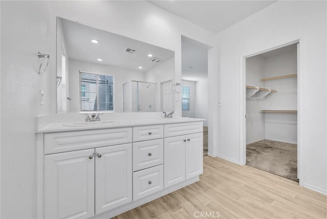 bathroom featuring vanity, wood-type flooring, plenty of natural light, and walk in shower