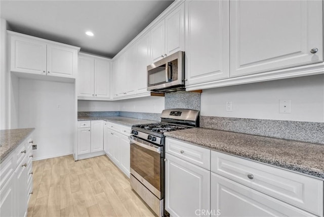 kitchen featuring white cabinetry, light stone counters, light hardwood / wood-style flooring, and stainless steel appliances