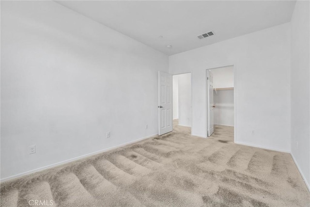 unfurnished bedroom with a spacious closet and light colored carpet