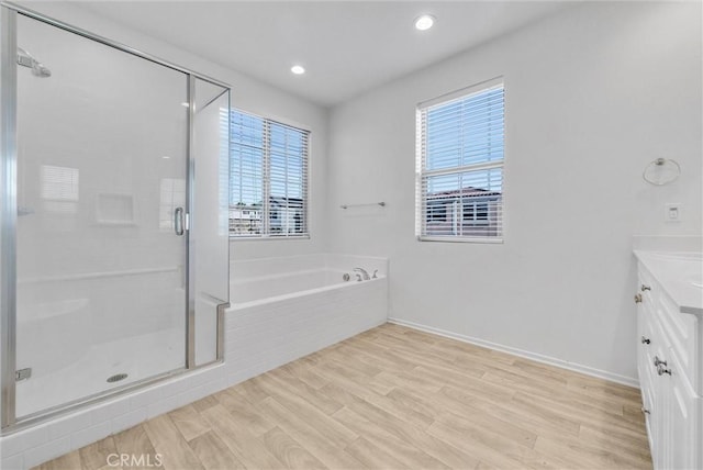 bathroom with plus walk in shower, hardwood / wood-style floors, and vanity