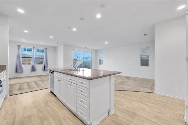 kitchen with sink, dishwasher, light hardwood / wood-style floors, an island with sink, and white cabinets