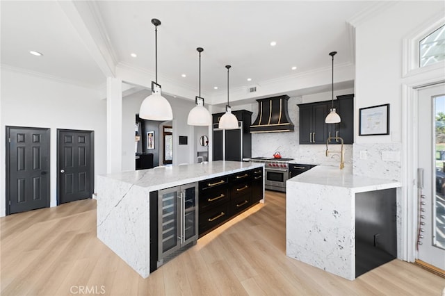 kitchen featuring wine cooler, pendant lighting, custom range hood, and a kitchen island