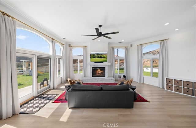 living room with ornamental molding, ceiling fan, and light hardwood / wood-style floors