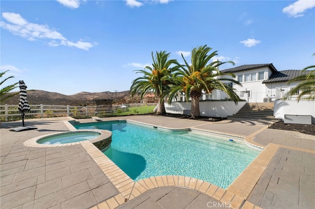 view of pool featuring an in ground hot tub, a mountain view, and a patio area