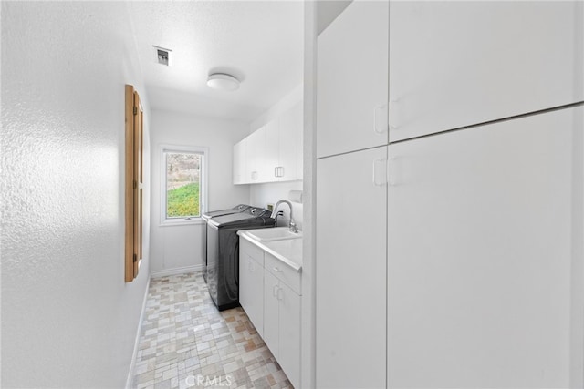 laundry area featuring sink, washer and clothes dryer, cabinets, and a textured ceiling