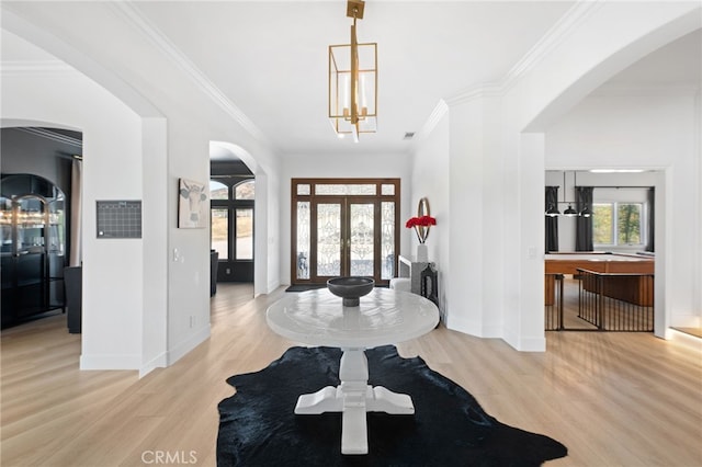 foyer entrance with crown molding, plenty of natural light, a chandelier, and light wood-type flooring