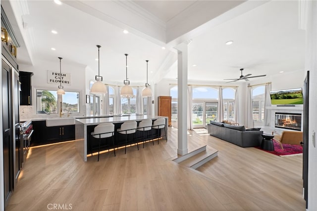 kitchen with crown molding, a center island, light wood-type flooring, pendant lighting, and backsplash