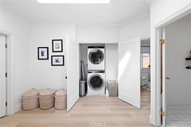 laundry area featuring stacked washer and dryer, light hardwood / wood-style flooring, and ornamental molding