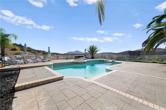 view of pool featuring a mountain view, a patio area, and an in ground hot tub