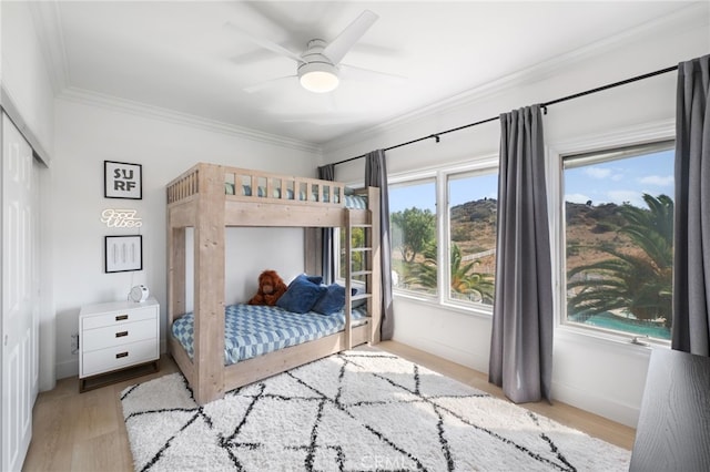 bedroom featuring crown molding, ceiling fan, light hardwood / wood-style floors, and a closet