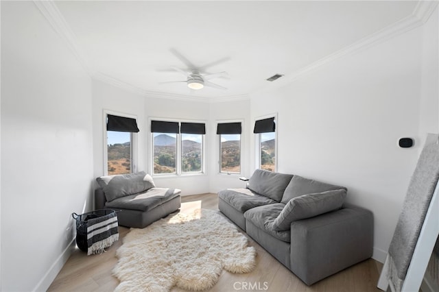 living room with crown molding, ceiling fan, and light wood-type flooring