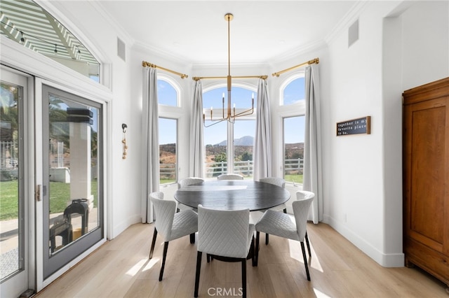 dining room featuring ornamental molding, a mountain view, a notable chandelier, and light hardwood / wood-style floors