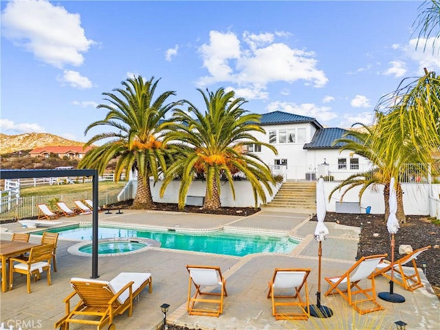 view of pool with an in ground hot tub, a mountain view, and a patio area