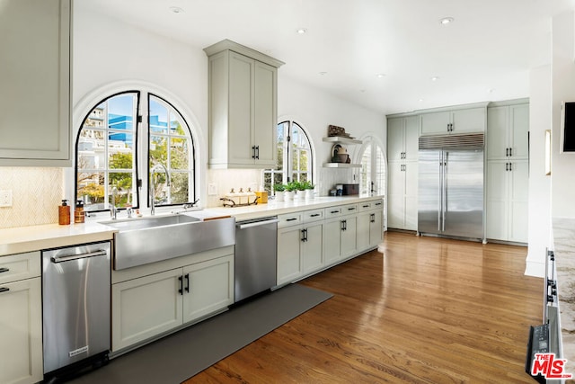 kitchen with hardwood / wood-style flooring, appliances with stainless steel finishes, sink, and backsplash