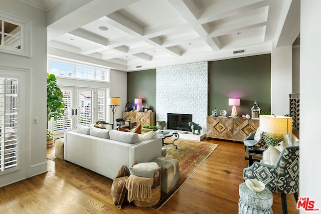 living room with a fireplace, light wood-type flooring, coffered ceiling, beam ceiling, and french doors