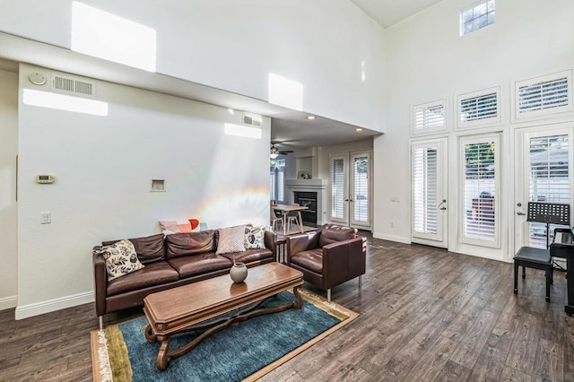 living room with ceiling fan, dark hardwood / wood-style floors, a healthy amount of sunlight, and a high ceiling